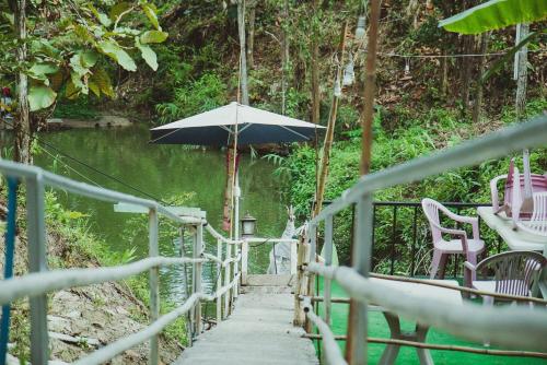 a bridge with an umbrella next to a river at Baansuan Chomchun in Amphoe Mae Taeng