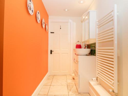 - une cuisine avec des murs orange et une porte blanche dans l'établissement Chapel Cottage, à Stroud