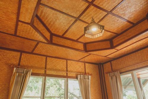 a ceiling with a light in a room with windows at Baansuan Chomchun in Amphoe Mae Taeng