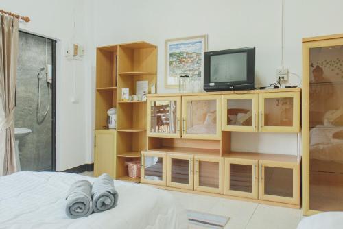 a living room with a television and a bed at Baansuan Chomchun in Amphoe Mae Taeng
