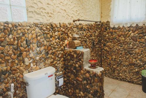 a bathroom with a stone wall next to a toilet at Baansuan Chomchun in Amphoe Mae Taeng