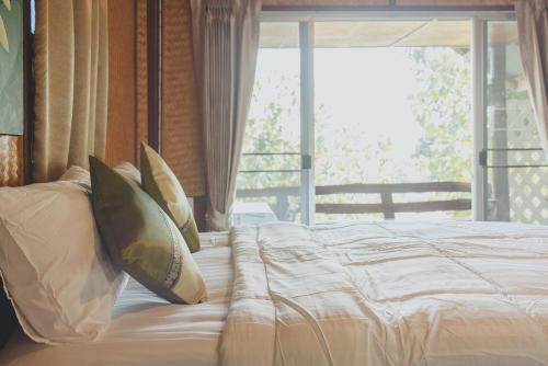 a bedroom with a bed with pillows and a window at Baansuan Chomchun in Amphoe Mae Taeng