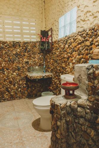a bathroom with a toilet and a stone wall at Baansuan Chomchun in Amphoe Mae Taeng