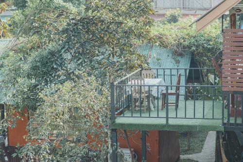 a table and chairs on a balcony next to a tree at Baansuan Chomchun in Amphoe Mae Taeng