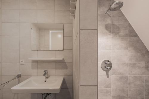 a white bathroom with a sink and a shower at Villa Zeezicht in Noordwijk