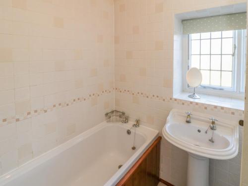 ein weißes Badezimmer mit Badewanne und Waschbecken in der Unterkunft Howe Green Cottage in York