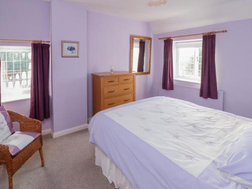 ein Schlafzimmer mit einem Bett und einem Stuhl und Fenstern in der Unterkunft Howe Green Cottage in York