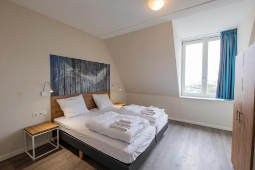 a bedroom with a bed with white sheets and a window at Villa Zeezicht in Noordwijk