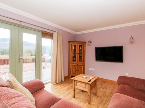 a living room with a couch and a tv at Little Tigh Clovelly in Spean Bridge