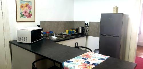 a kitchen with a counter with a refrigerator and a microwave at Kelkiewyn Guesthouse Caledon in Caledon
