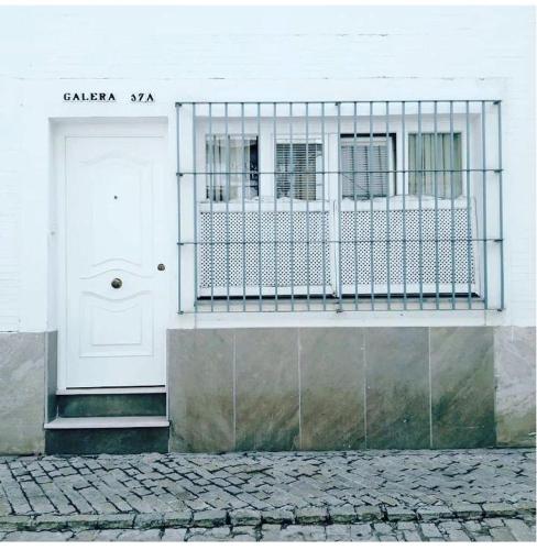 - un bâtiment blanc avec une porte blanche et un balcon dans l'établissement Coqueto Apartamento en el Arenal, Centro, à Séville
