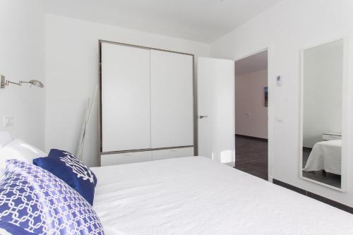 1 dormitorio con cama blanca y espejo en Apartamento Gama 1 habitación, en Cala Galdana