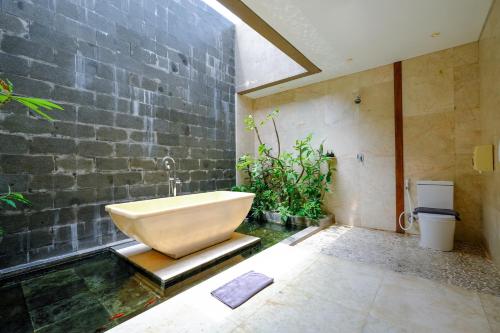 a bathroom with a bath tub and a stone wall at The Westlake Hotel & Resort Yogyakarta in Yogyakarta