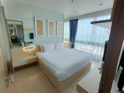 a bedroom with a white bed and a large window at Veranda Residence by VS in Na Jomtien