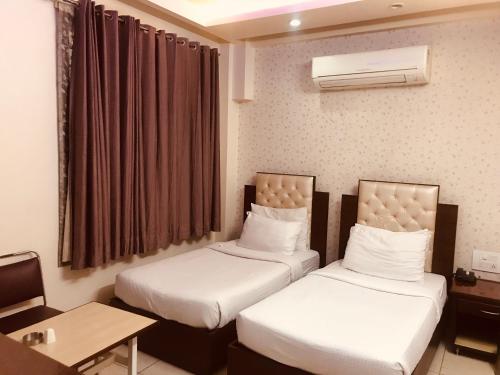 een hotelkamer met 2 bedden en een tafel bij Leela Residency in Karnal