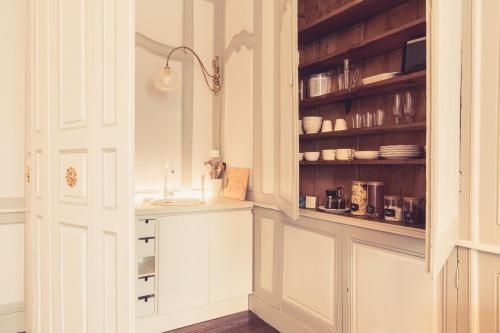 uma cozinha com armários brancos e um lavatório em La Maison de la Liberté Suite Jeanne Barret em Poitiers