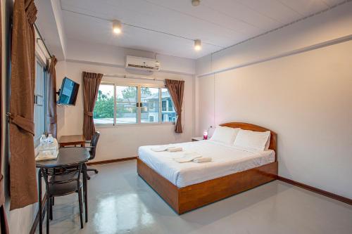 a bedroom with a bed and a table and a window at Kanyanat Boutique Hotel in Lampang