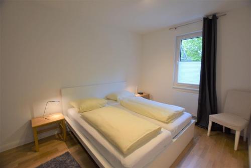 Un dormitorio con una cama y una silla y una ventana. en Ferienwohnung-Moin, en Hohwacht