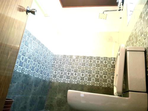 a bathroom with a toilet and a tiled wall at Mount View Inn in Kandy