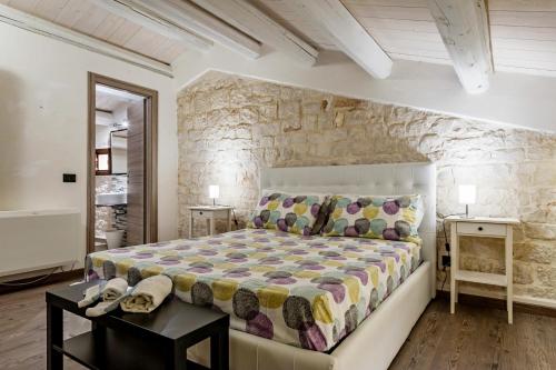 sypialnia z dużym łóżkiem i kamienną ścianą w obiekcie Villa Antica Aia Relax w mieście Scicli