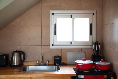 a kitchen with two pots and a sink and a window at Cabaña Anita in Merlo