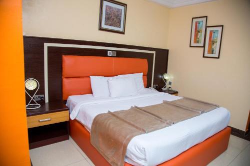 a bedroom with a large bed with an orange headboard at Sweet Spirit Hotel and Suites Danag - Port Harcourt in Port Harcourt