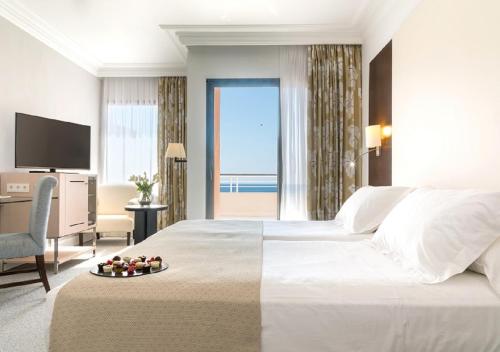 a hotel room with two beds and a television at GPRO Valparaiso Palace & Spa in Palma de Mallorca