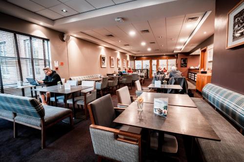 a restaurant with tables and chairs and people sitting at tables at The Warwickshire Hotel and Country Club in Warwick