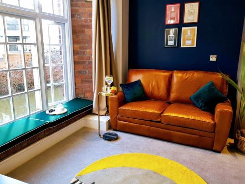 a living room with a brown couch and a window at Cocoa Lily - River fronted studio with secure parking in York
