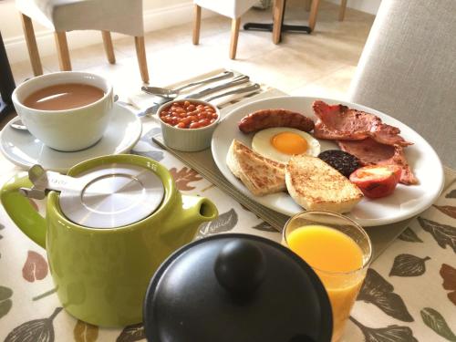 una mesa de desayuno con un plato de huevos tocino y café en Mourne Country House Bed and Breakfast, en Kilkeel