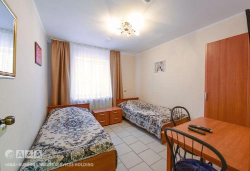 a hotel room with two beds and a desk at Viktoria Hotel in Cherepovets