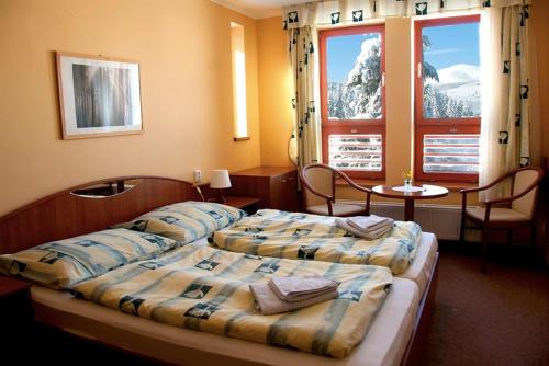 1 dormitorio con 2 camas, mesa y ventanas en Renerovka 93 en Dolní Malá Úpa