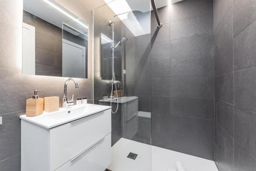 La salle de bains est pourvue d'un lavabo blanc et d'un miroir. dans l'établissement Sant Pau Ramblas Apartments Serennia, à Barcelone