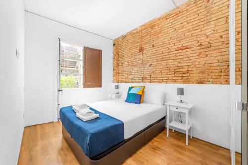 - une chambre avec un lit et un mur en briques dans l'établissement Sant Pau Ramblas Apartments Serennia, à Barcelone