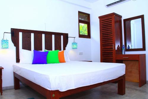 a bedroom with a large bed with colorful pillows at Villa 45 - Balapitiya in Balapitiya