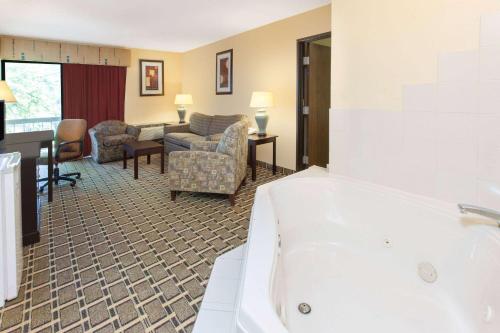 a bathroom with a bath tub and a living room at Days Inn & Suites by Wyndham Madison Heights MI in Madison Heights