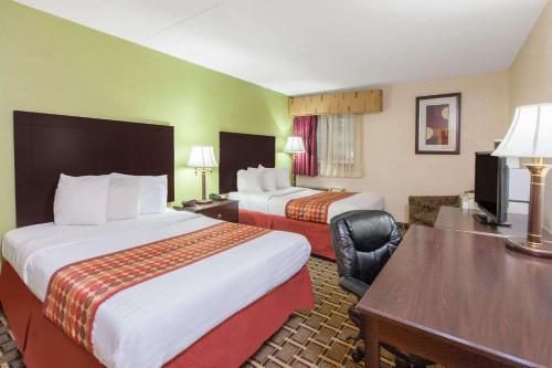 a hotel room with two beds and a desk at Days Inn & Suites by Wyndham Madison Heights MI in Madison Heights