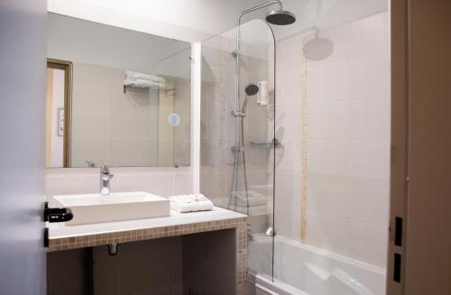 a bathroom with a shower, sink, and mirror at Hotel Port Marine in Sète