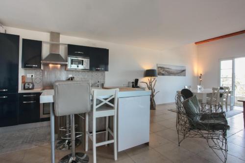 une cuisine avec des armoires noires, une table et des chaises dans l'établissement CAPO BIANCO - Cap Corse et Vue Mer, à Ersa