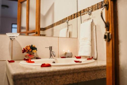 a bathroom sink with red flowers and a candle at Lunandina Huaraz in Huaraz