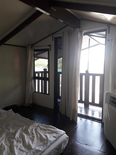 a bedroom with a bed and an open door to a balcony at Maena Water Chalets in Tumpat