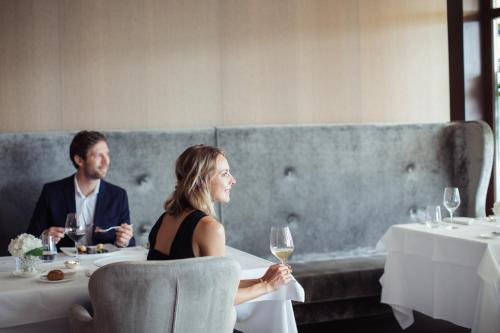 a man and woman sitting at a table with wine glasses at Giardino Marling in Merano