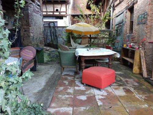 d'une terrasse avec une table, un parasol et un tabouret rouge. dans l'établissement La chambre rose, à Rosenwiller