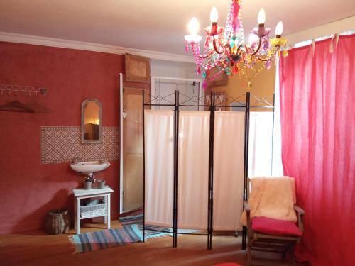 a bathroom with red walls and a chandelier at La chambre rose in Rosenwiller