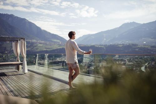 a man standing on a balcony with a glass of wine at Giardino Marling in Merano