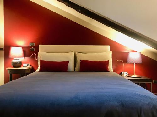 トリノにあるSanti apartment in the heart of Turinのベッドルーム1室(赤い壁のベッド1台、ランプ2つ付)