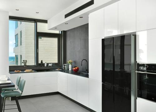 una cocina con armarios blancos y electrodomésticos negros en High Standing at Hayarkon by HolyGuest, en Tel Aviv