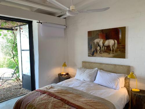 a bedroom with a bed and a painting of horses at Kleinkloof Farm in Piketberg
