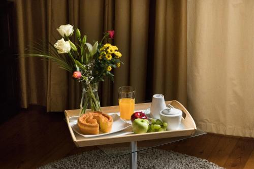 ein Tablett mit Frühstückslebensmitteln und einer Vase Blumen in der Unterkunft Guest House Bairro Azul in Lissabon