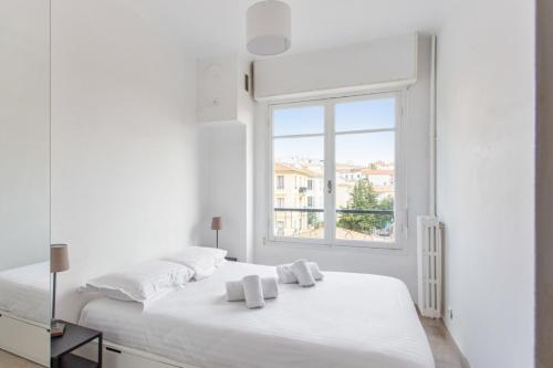 une chambre blanche avec un grand lit blanc et une fenêtre dans l'établissement Appartement Libération - Welkeys, à Nice